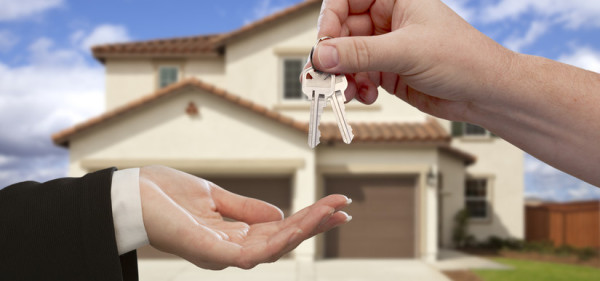 Handing Over the House Keys in Front of a Beautiful New Home.